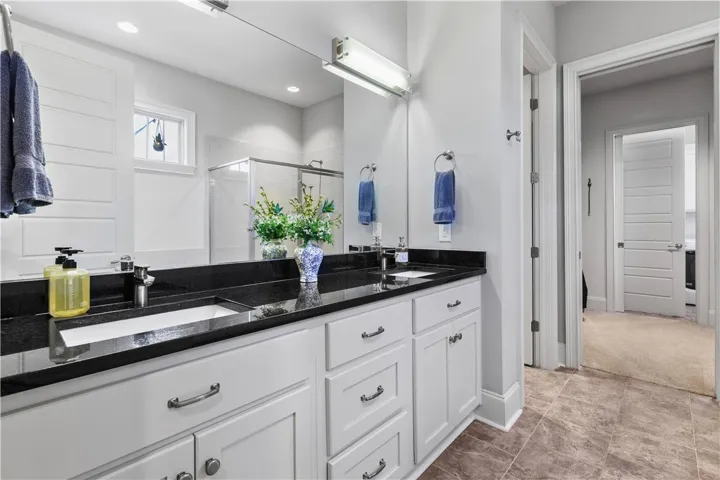 A spacious double vanity with dark stone countertops anchors this modern tiled bathroom.