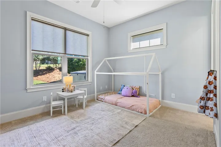 High ceilings and generous natural light highlight this comfortable carpeted bedroom.