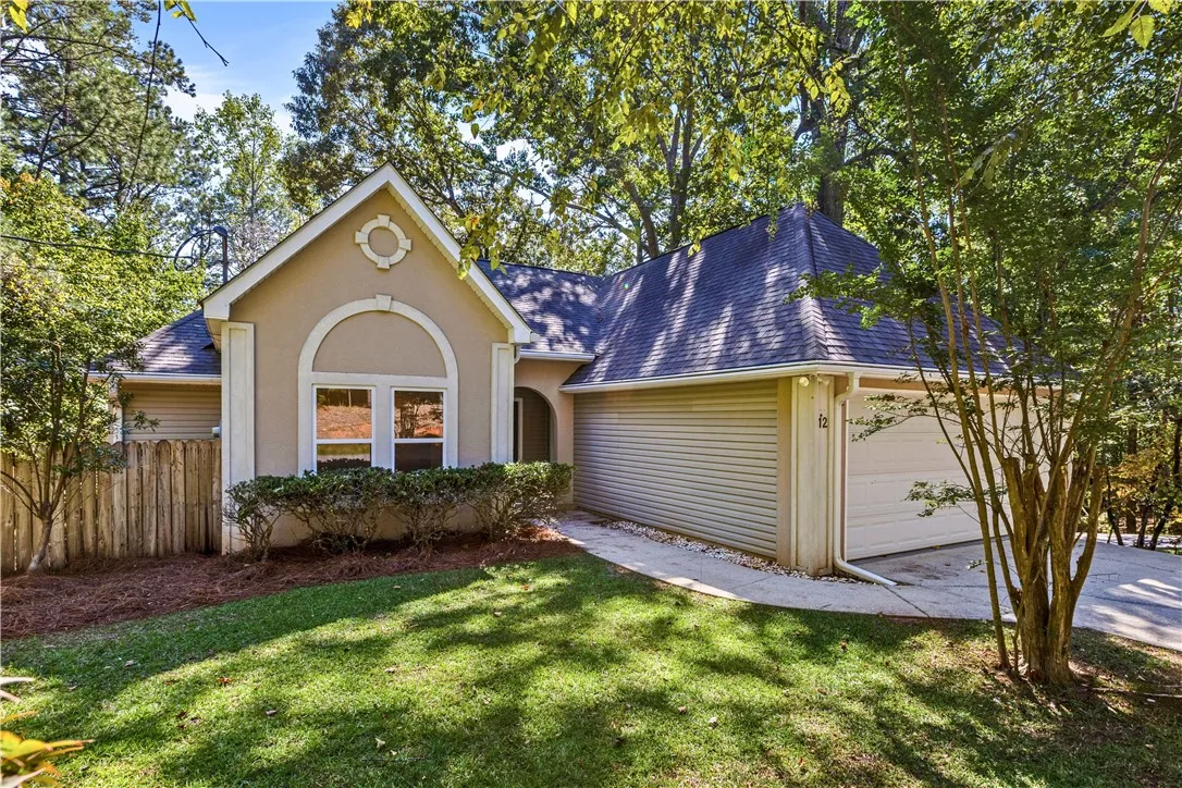 Mature trees frame the architectural lines of this multi-gabled home with an attached garage.