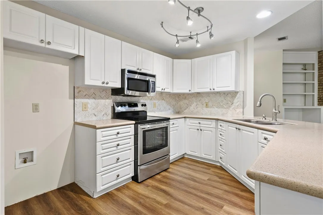 Gleaming wood-look floors anchor this classic kitchen featuring a tiled backsplash and ample cabinetry. New dishwasher and backsplash