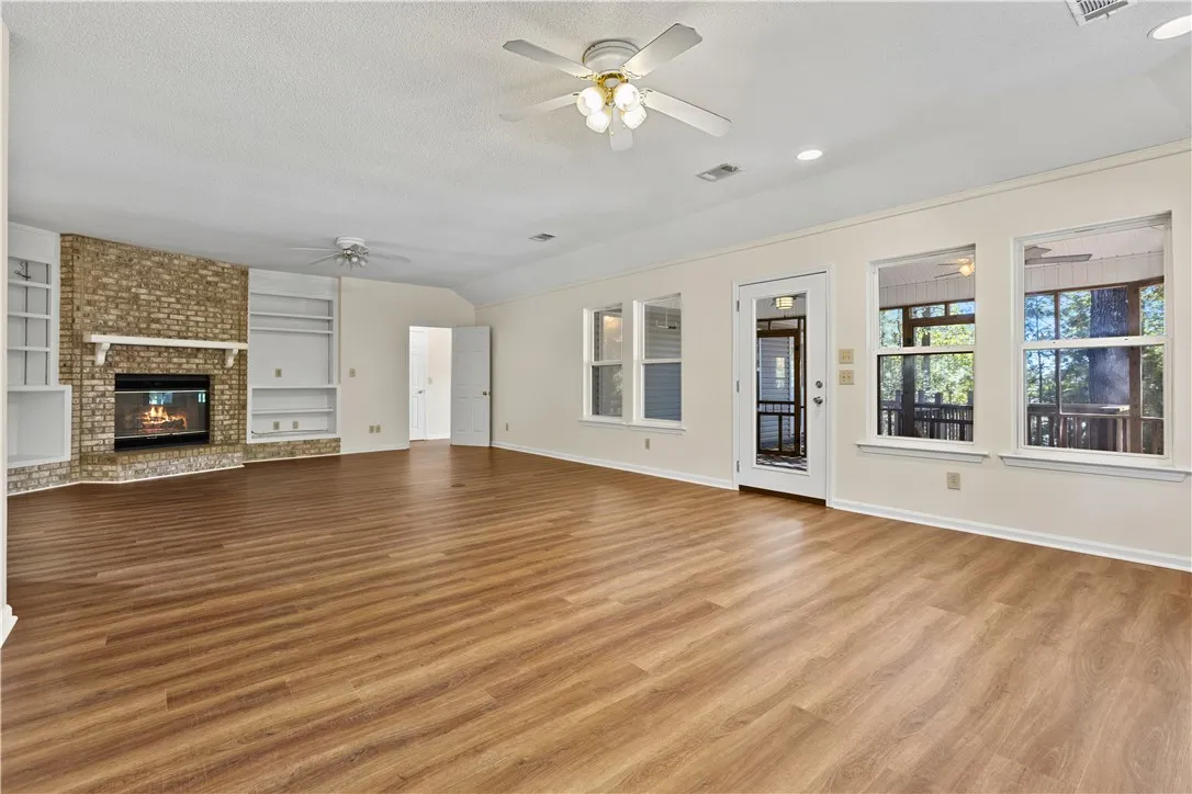 Warm wood-look flooring and a brick fireplace define this spacious living area.