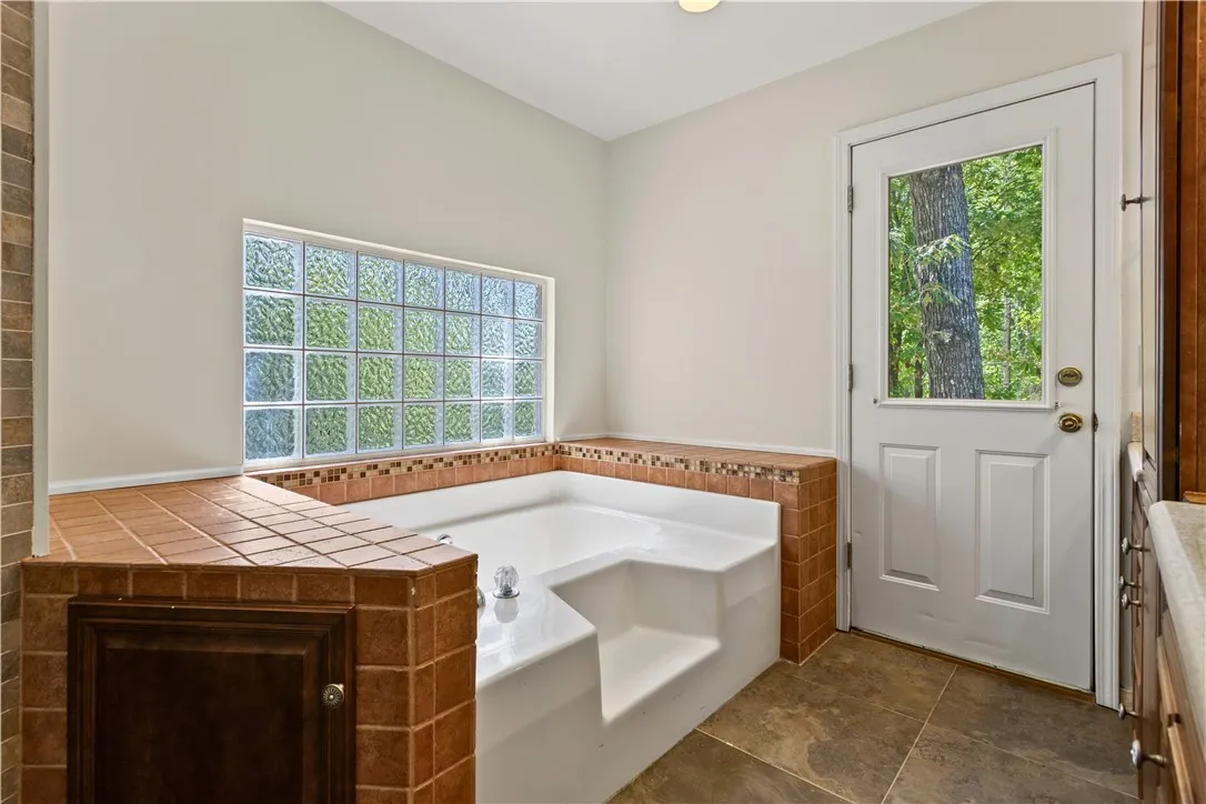 Natural light filters through glass block windows onto the tiled surround of a soaking tub.