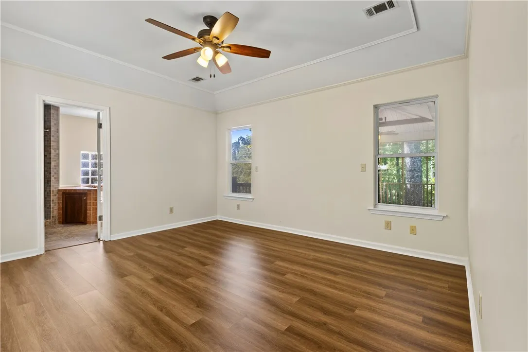 Rich wood-inspired LVP floors and elegant crown molding define this serene primary suite.