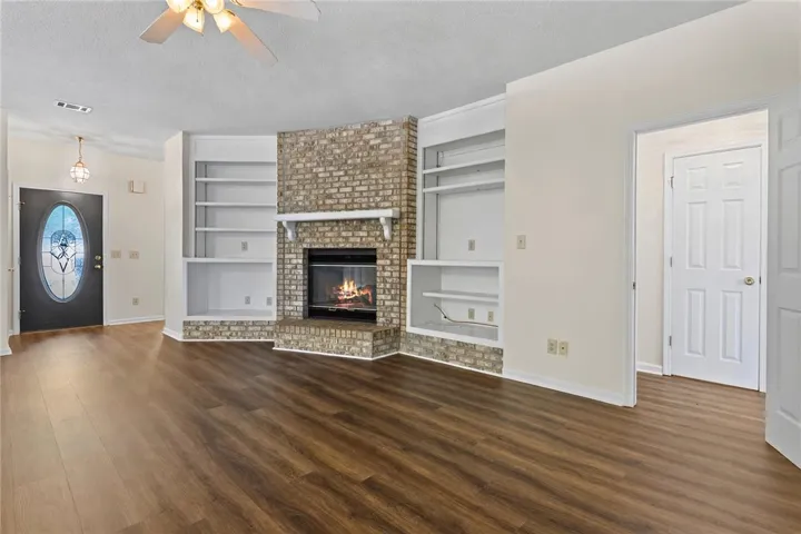 Rich wood-look flooring and a brick fireplace anchored by custom built-ins define this inviting room.