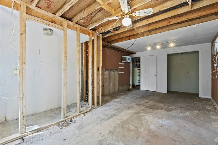 An unfinished basement area presents a blank canvas with exposed framing and concrete floors. New a/c wall unit