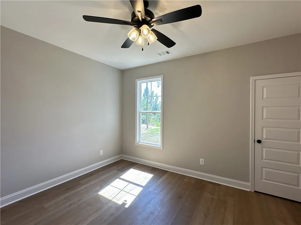 Rich wood-plank flooring pairs with a tall window overlooking serene greenery.
