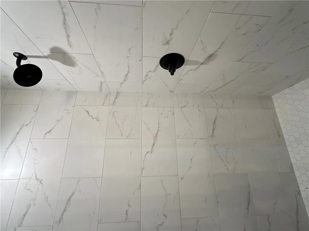 Floor-to-ceiling marble-patterned tile creates a clean and modern aesthetic in this custom shower.