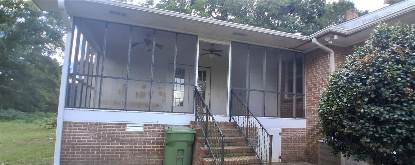 Brick stairs ascend to a spacious screened porch overlooking the  yard.