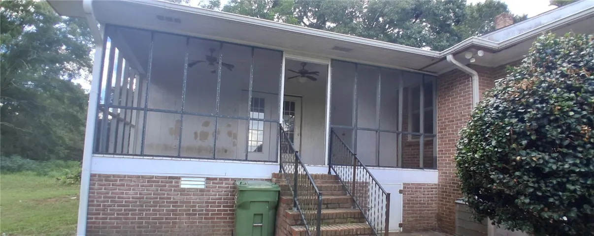 Brick stairs ascend to a spacious screened porch overlooking the  yard.