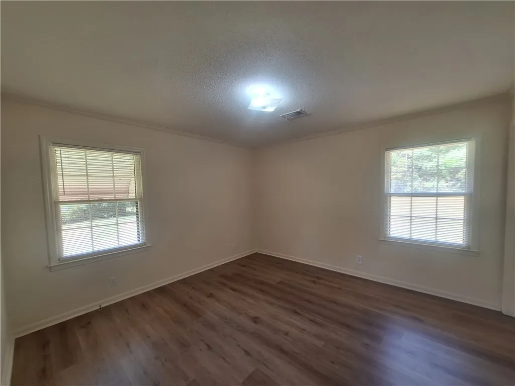 Classic wood-look flooring and dual windows highlight this versatile bedroom space.