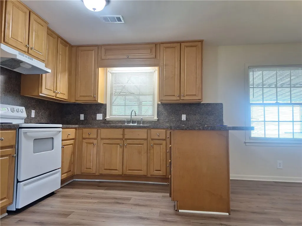 Warm wood cabinetry and durable vinyl flooring define this functional kitchen layout.