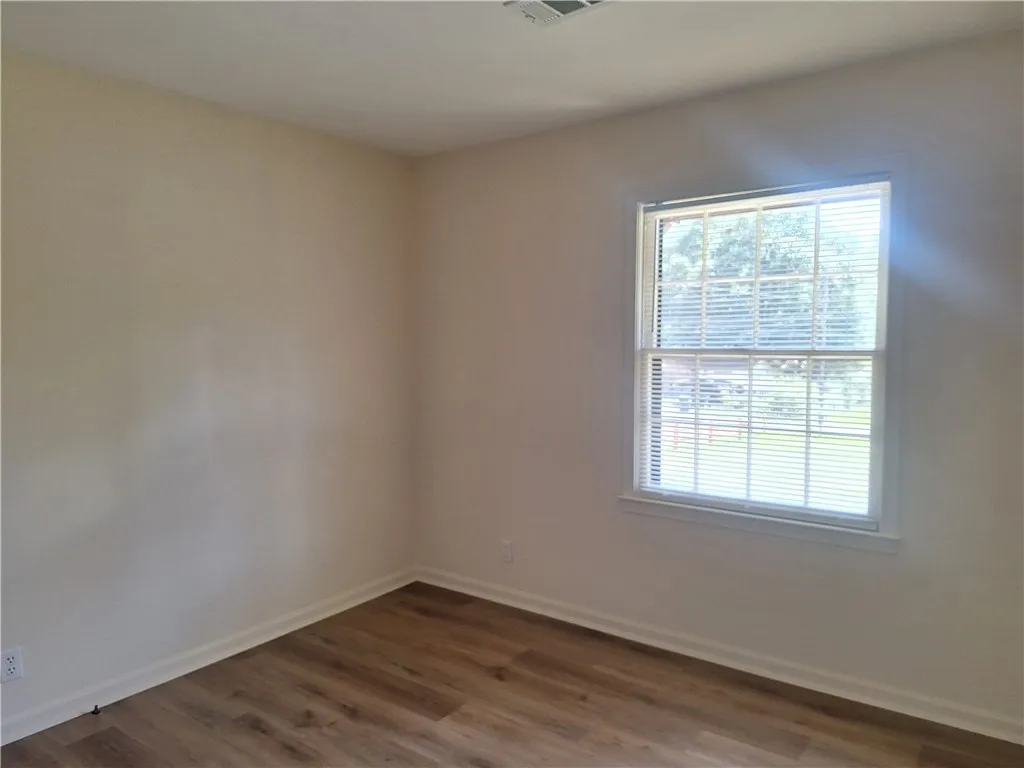 Gleaming wood floors anchor this versatile room illuminated by natural light from a large window.