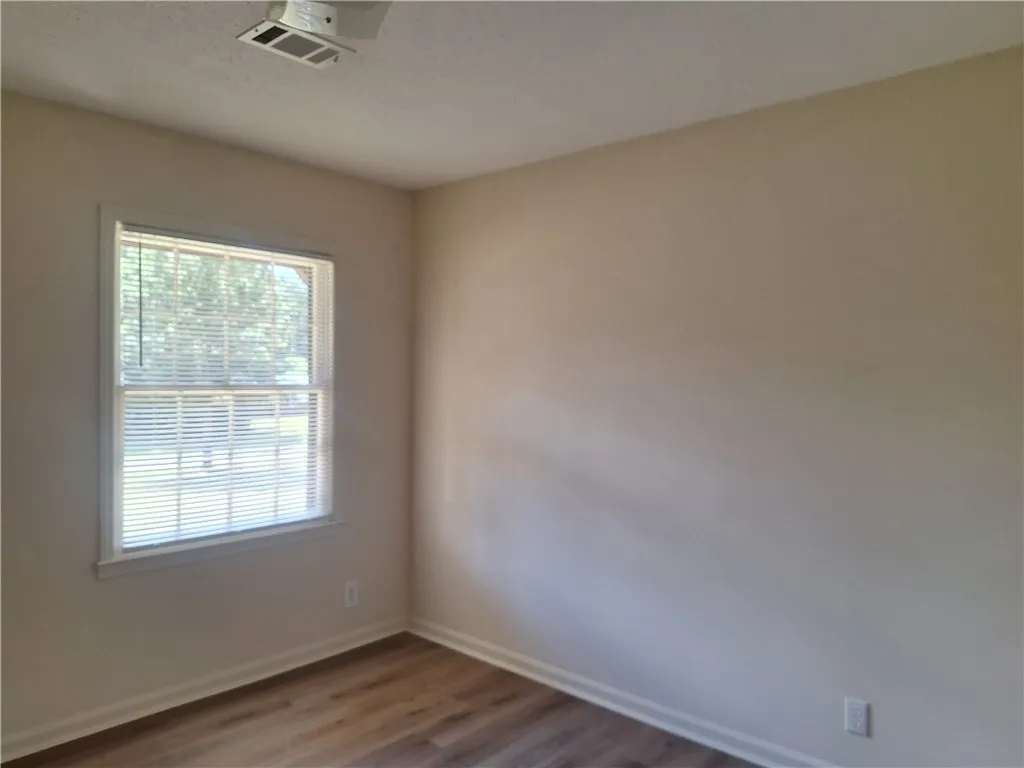 A window with classic blinds overlooks the yard from this versatile bedroom.