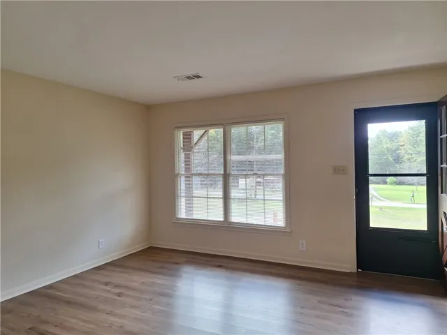 Smooth wood-style flooring anchors this versatile space, complete with a glass-paneled entry door.