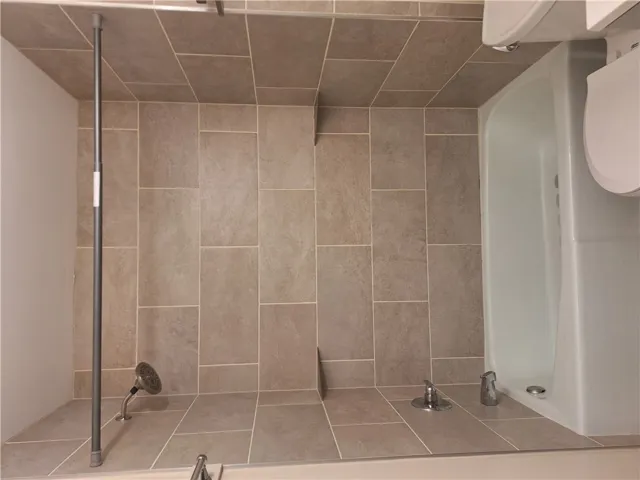 Elegantly tiled walls surround a clean tub and shower combination.