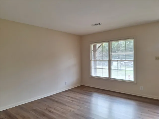 Smooth wood flooring and a wide double window define this versatile interior space.