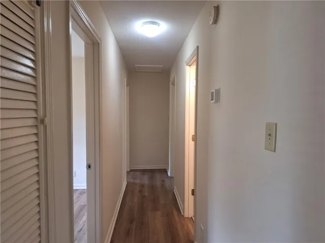 A straightforward hallway links multiple rooms with practical wood-inspired flooring.