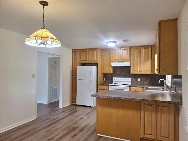 Ample wooden cabinetry and durable laminate flooring define this functional kitchen workspace.