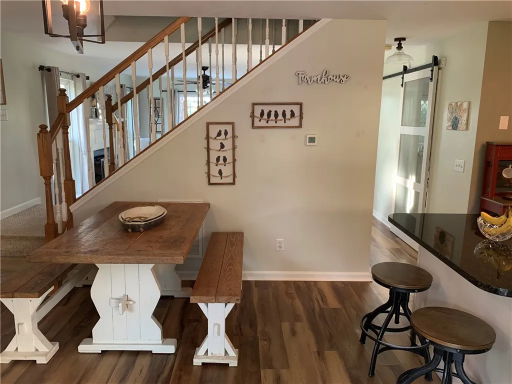 Rich wood-look flooring and an elegant wooden staircase anchor this inviting dining area.