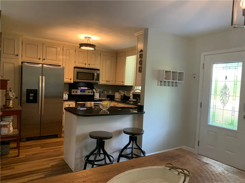 Rich wood flooring runs seamlessly from the cozy dining area into the adjacent kitchen.
