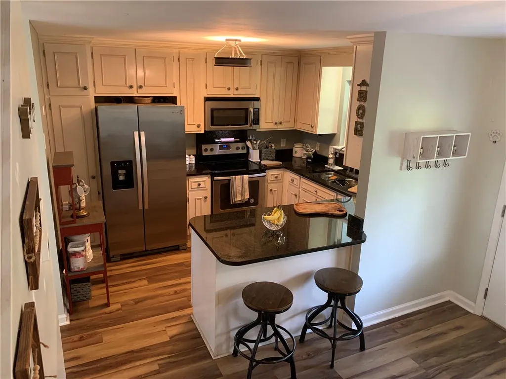 Rich wood floors anchor this kitchen workspace featuring stone countertops and built-in cabinetry.
