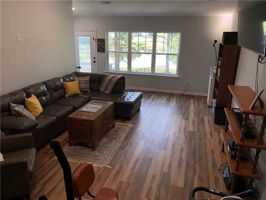 Warm wood flooring and water views define this comfortable, light-filled living area.
