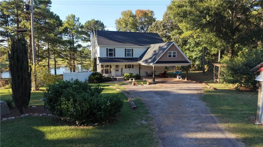A gravel driveway leads to this charming two-story residence featuring an attached carport.