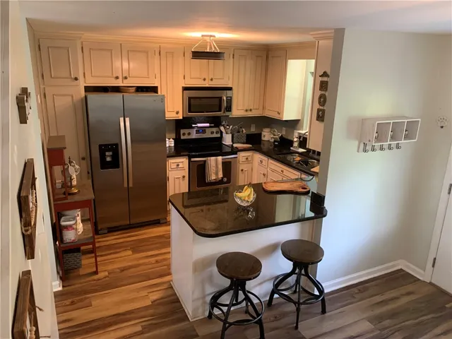 Rich wood floors anchor this kitchen workspace featuring stone countertops and built-in cabinetry.