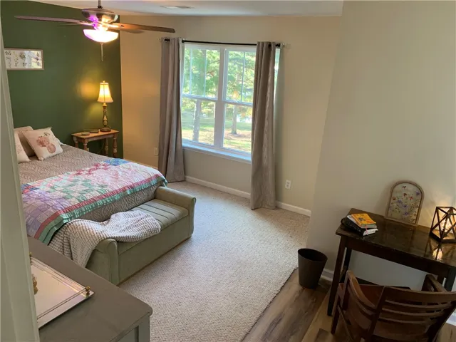 Natural light streams through double windows in a cozy bedroom with wall-to-wall carpeting.