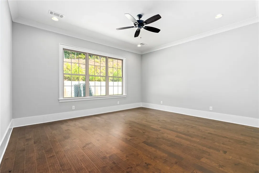 Rich hardwood flooring complements the pristine white walls and classic crown molding details.