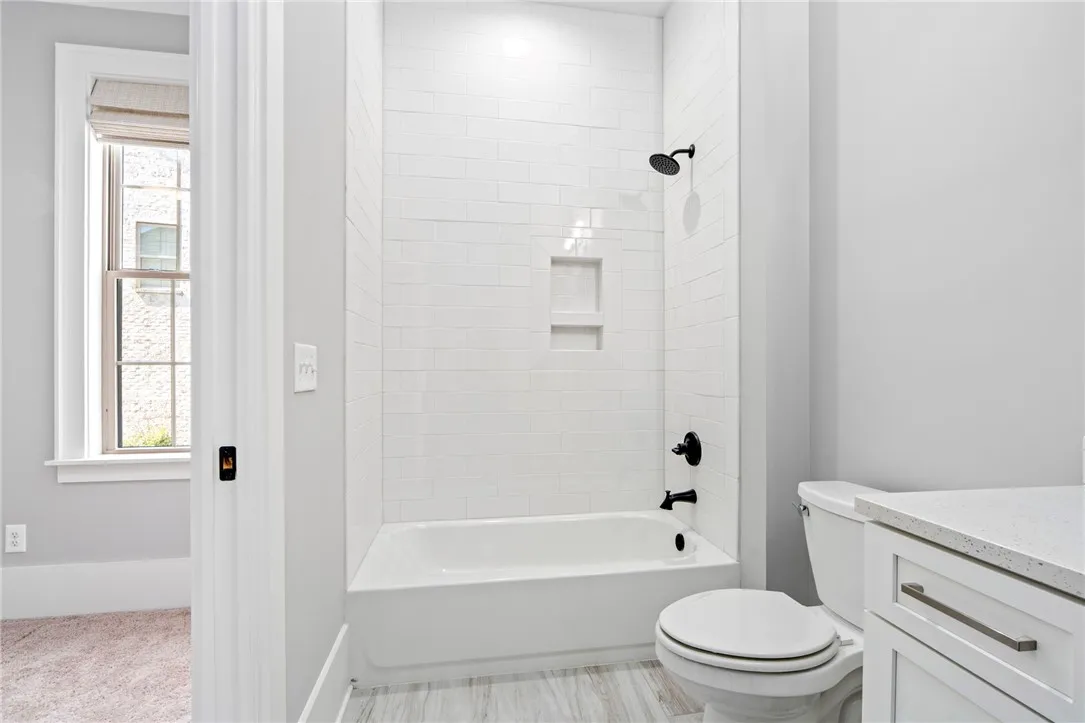 An alcove bathtub with pristine tile surround anchors this sleek, modern bathroom space.