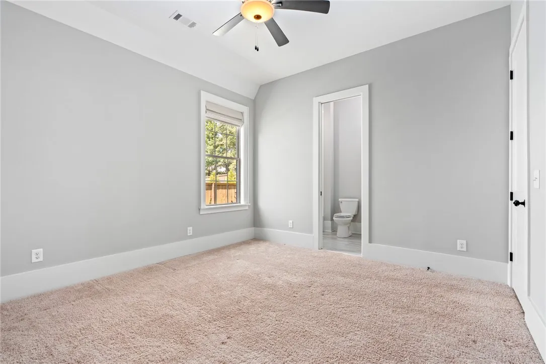 Plush carpeting and tray ceilings frame this comfortable bedroom with an attached bathroom.