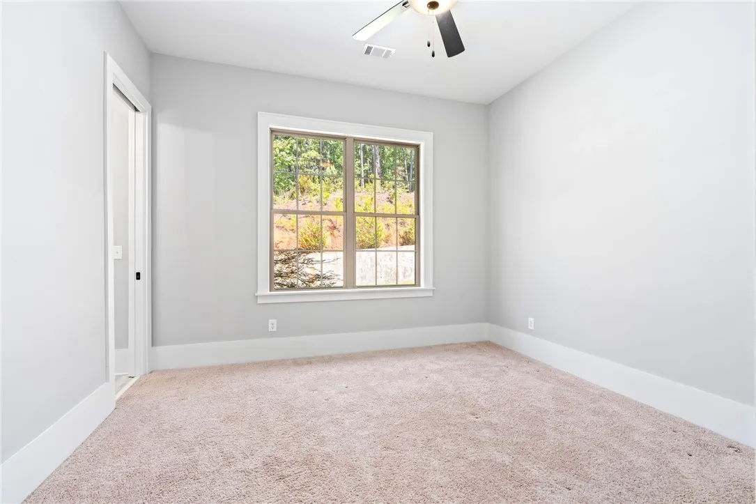 A spacious window frame welcomes natural light and views of nature over soft carpeting.
