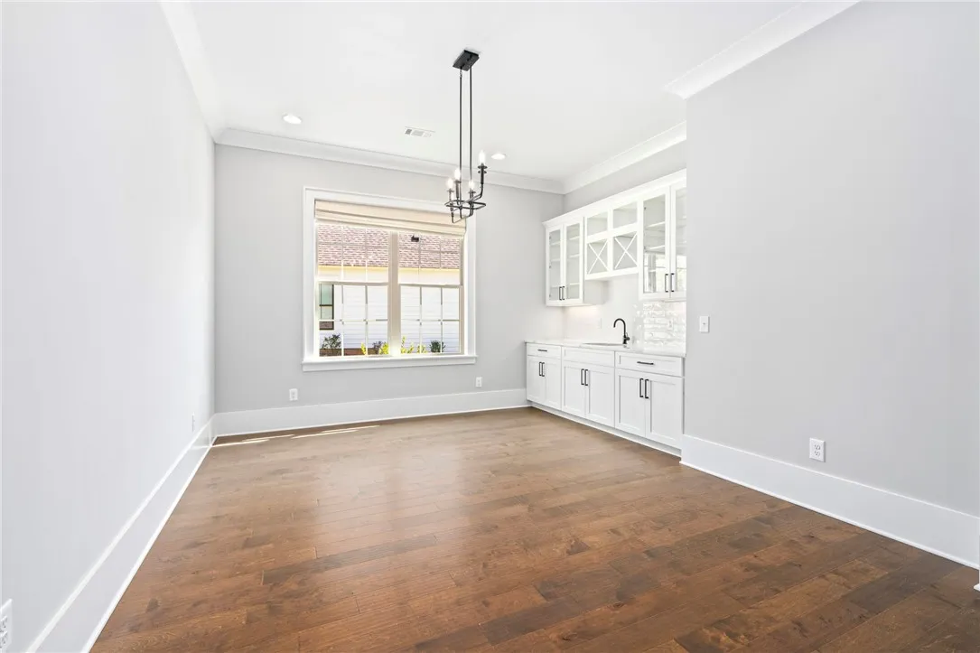 Rich hardwood flooring complements a built-in wet bar and elegant crown molding.