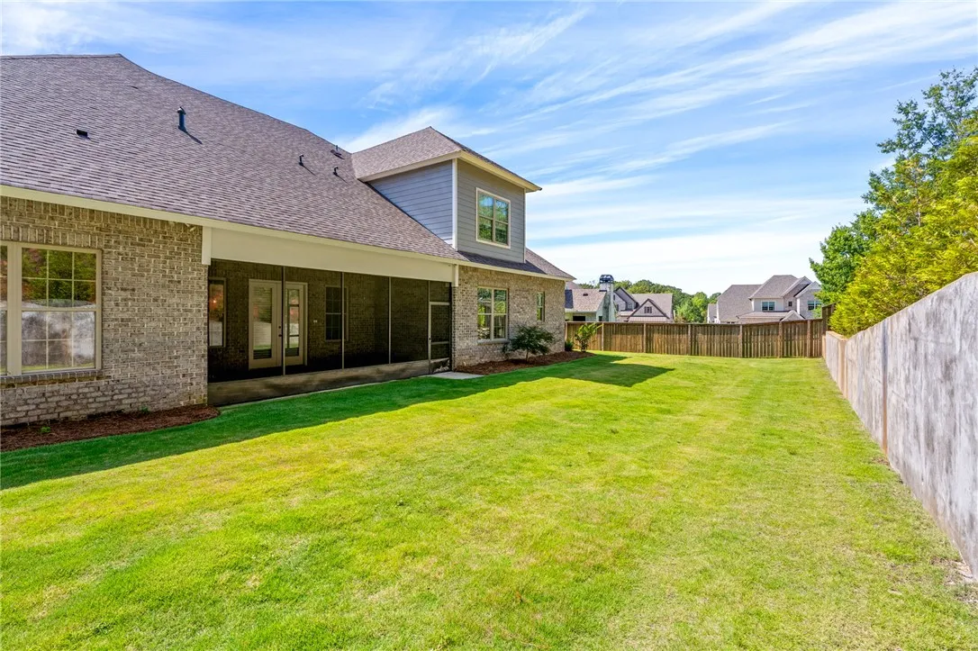 A spacious grassy lawn sits adjacent to the brick exterior and screened porch.