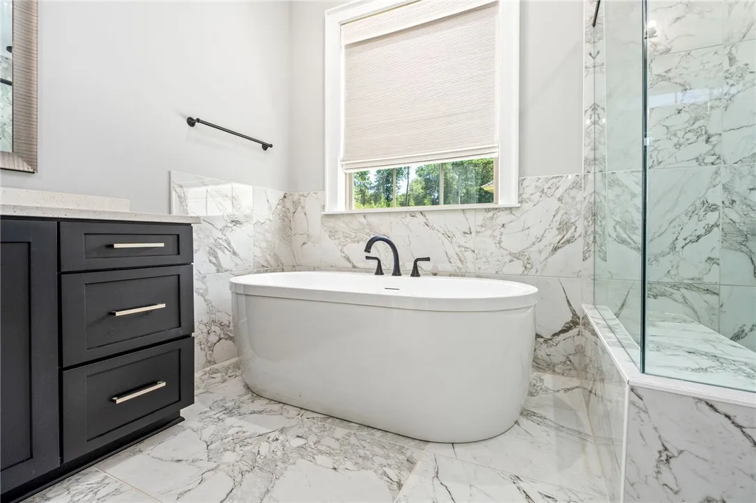 Elegance defines this space, showcasing marble tile floors and a freestanding soaking tub.