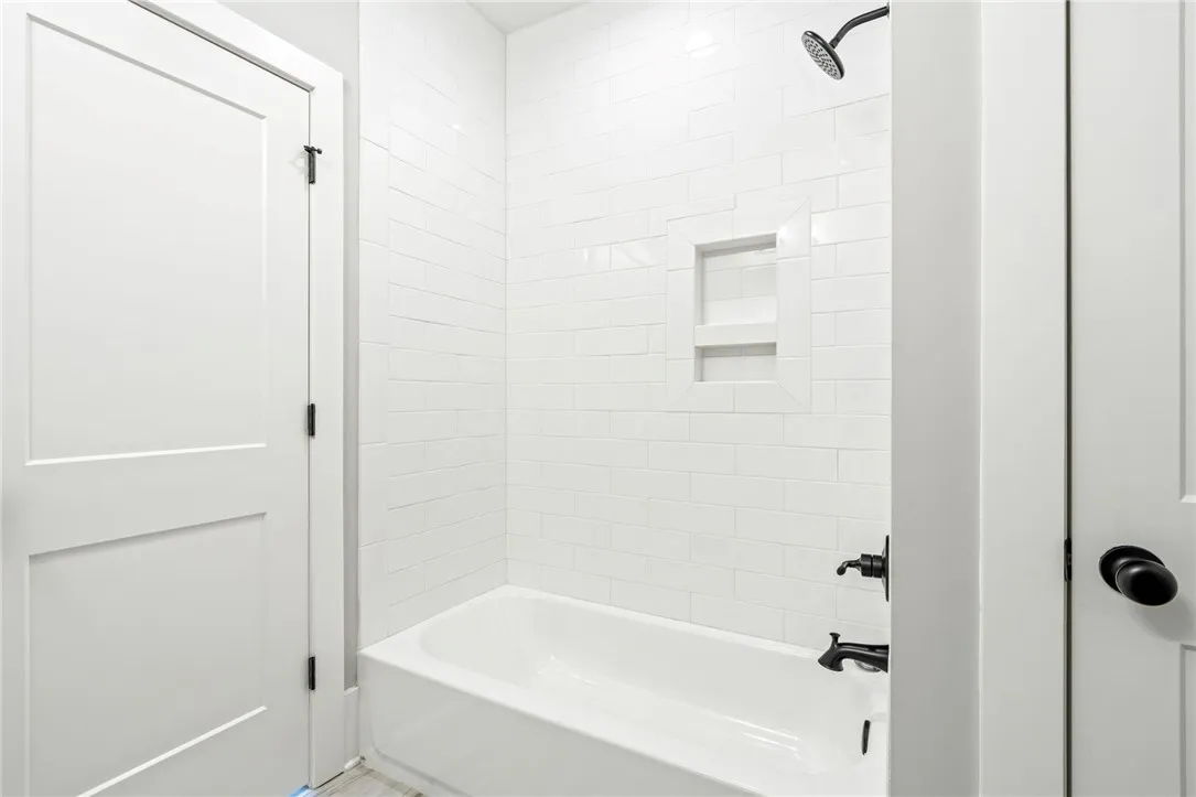 An elegant bathtub features timeless subway tile surround and integrated shelving.