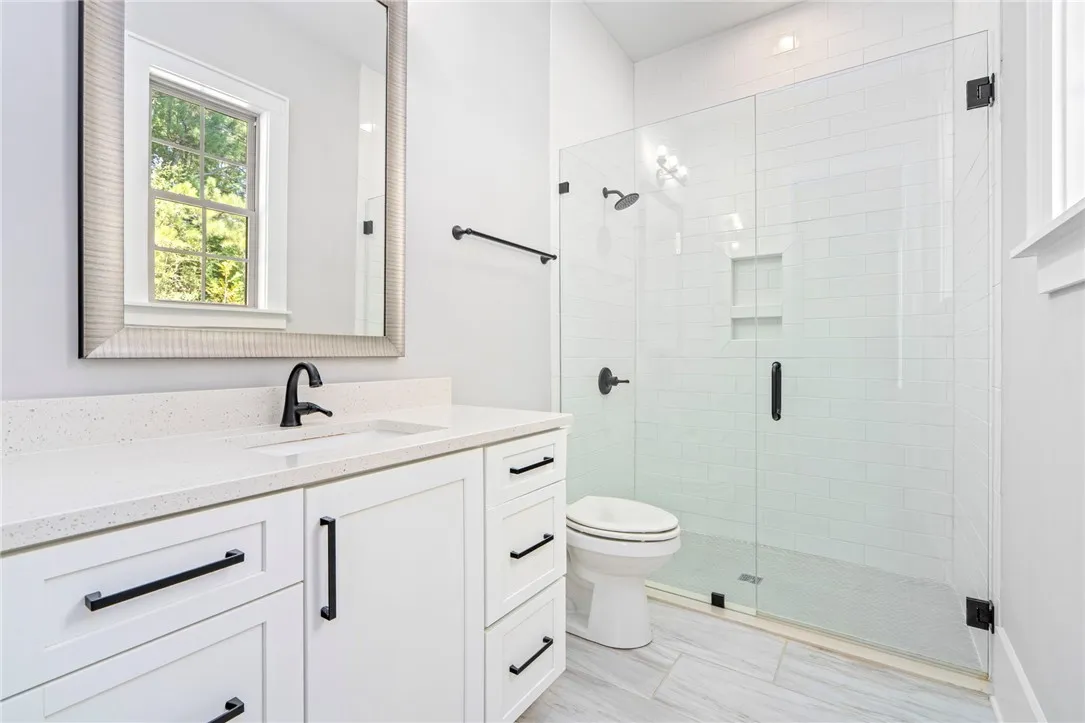 Gleaming stone counters pair beautifully with a glass-enclosed shower in this modern bathroom.