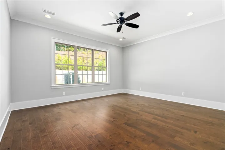 Rich hardwood flooring complements the pristine white walls and classic crown molding details.