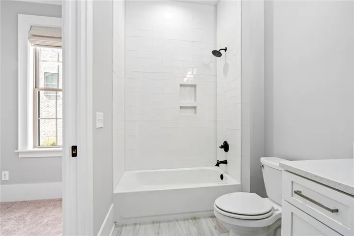 An alcove bathtub with pristine tile surround anchors this sleek, modern bathroom space.