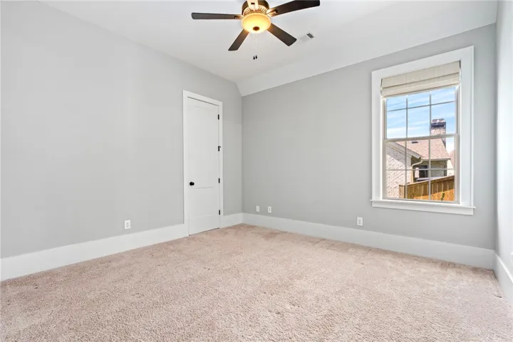 Plush carpeting anchors this bright bedroom beneath clean crown molding and classic trim work.