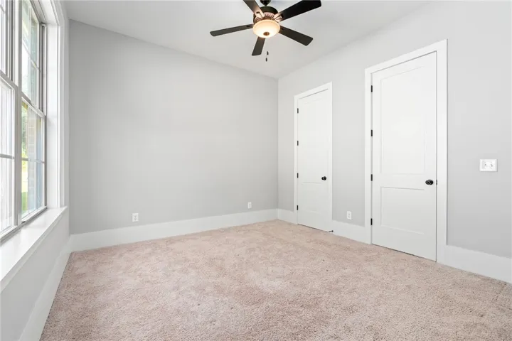 A spacious bedroom offers neutral walls and classic plush carpeting beneath high ceilings.