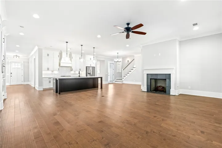 Rich engineered wood floors anchor this open concept layout under high ceilings with recessed lighting.