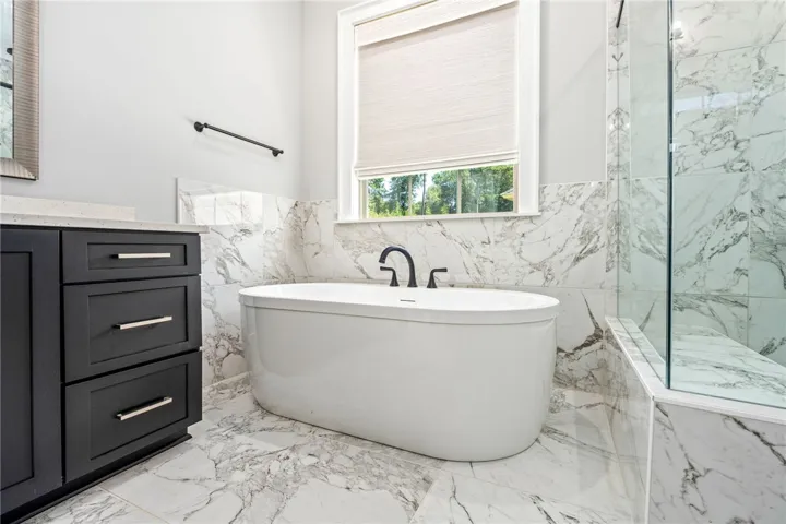 Elegance defines this space, showcasing marble tile floors and a freestanding soaking tub.