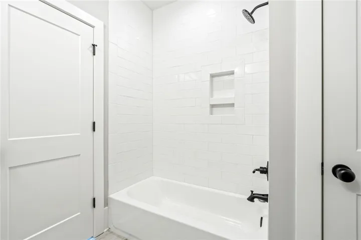 An elegant bathtub features timeless subway tile surround and integrated shelving.