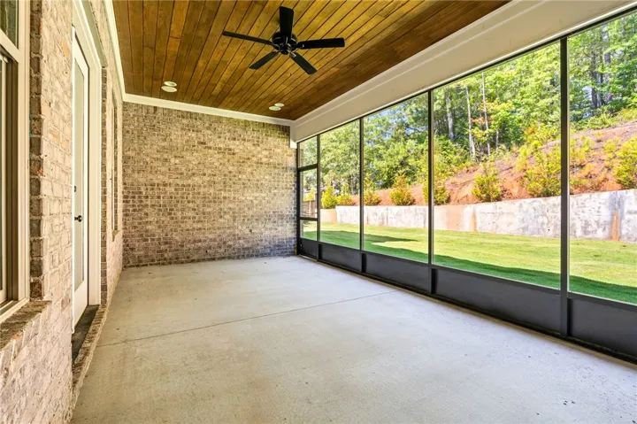 Brick accents and a wood ceiling define this spacious screened porch overlooking the yard.