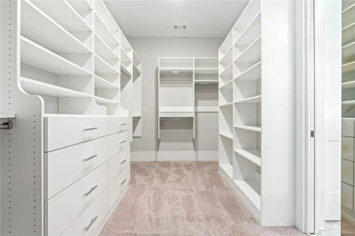 Ample built-in shelving and storage drawers maximize space in this meticulously designed walk-in closet.