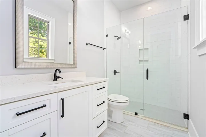 Gleaming stone counters pair beautifully with a glass-enclosed shower in this modern bathroom.