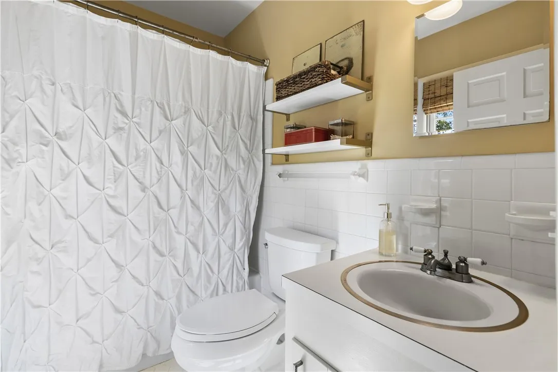 Classic white tiling and floating shelves maximize space in this primary bathroom.