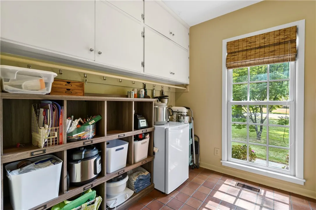 A functional laundry room features durable tile flooring and ample built-in storage.